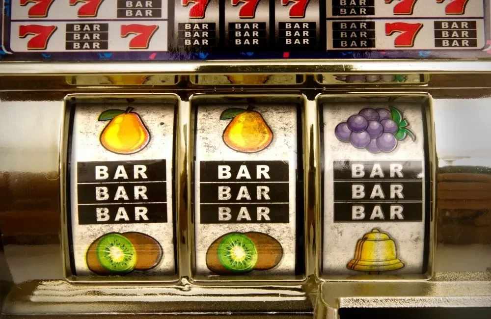 老虎機轉輪近拍，顯示 BAR 與水果符號排列